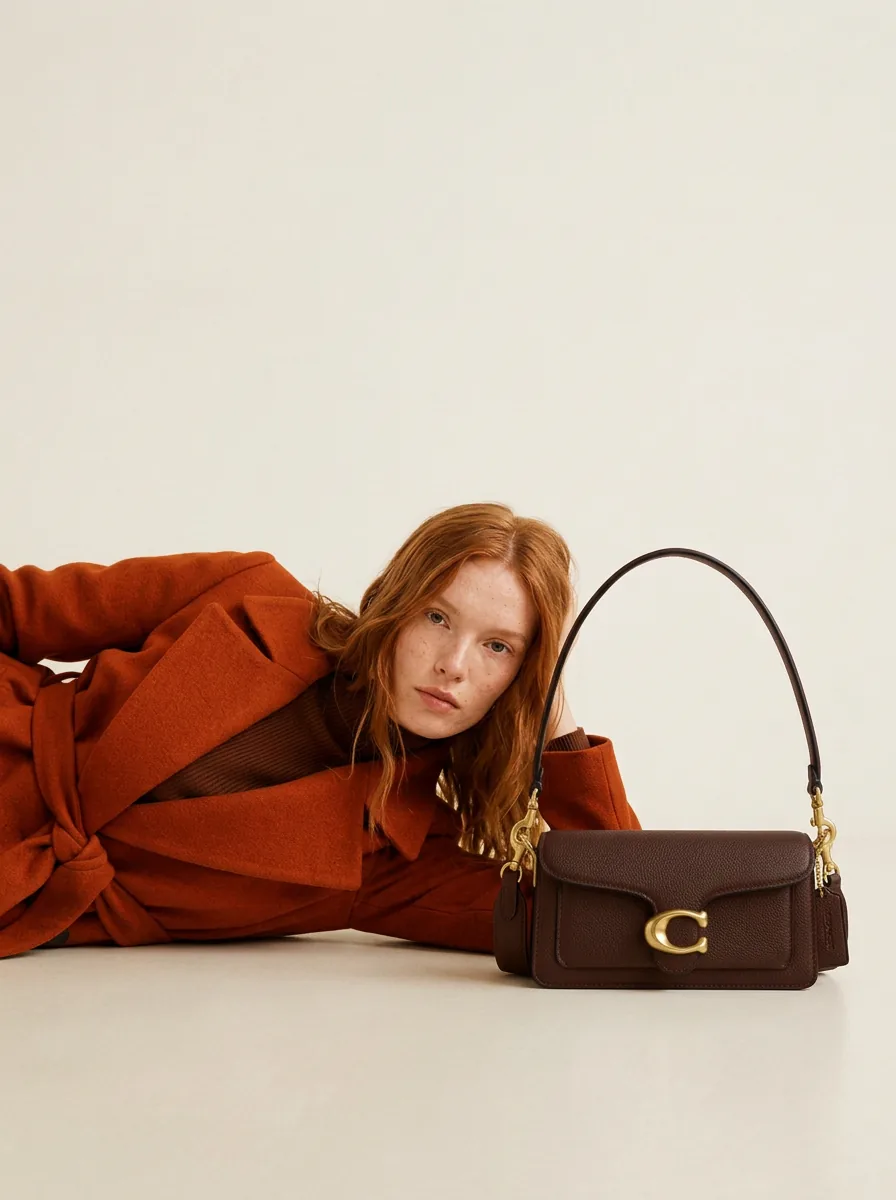 Modelo tumbada junto al bolso Coach